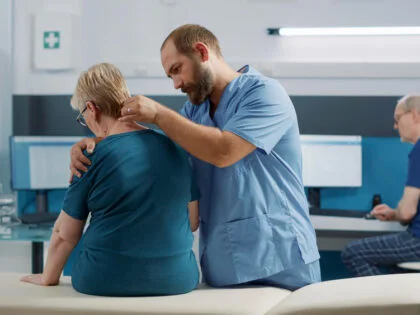 Health specialist doing osteopathy procedure on old patient with physical injury, cracking spinal cord bones for recovery