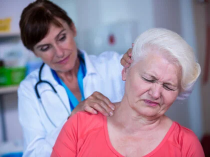 female doctor examining grey haired woman patient