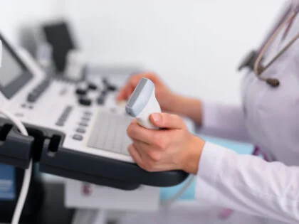 Young blonde doctor working on ultrasound machine in new clinic.