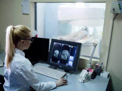 Radiologist analyzing brain MRI scan results of a patient on computer monitor in control room