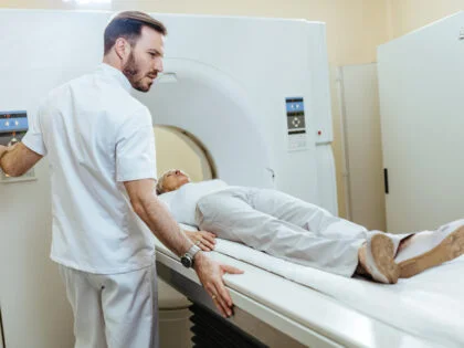 Medical technician starting MRI scanning examination of a female patient at medical clinic