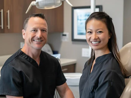 A man and woman are smiling in a room with a lamp above them