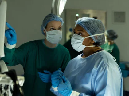 female surgeons in discussion, using medical equipment in operating theatre during operation. Hospital, medical and healthcare services.