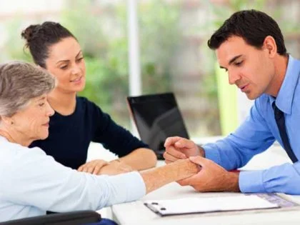 e-Dermatology - a male doctor examines an elderly woman's hand as a young woman looks on