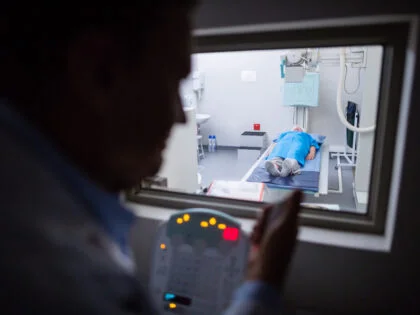 Doctor using x-ray unit control panel on patient