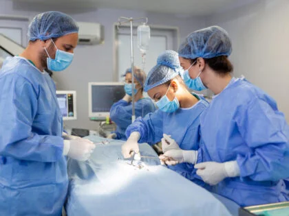 Surgeons operating below lighting equipment Male and female doctors are wearing blue scrubs They are working in hospital