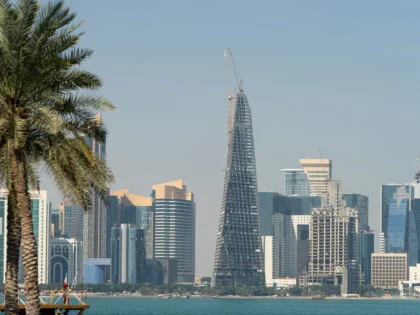 Panoramic view of modern skyline of Doha through blurred palm trees. Qatar on sunny day.