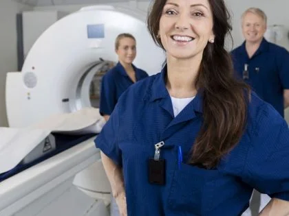 two female and one male pratitioner in nave blue scrubs in an MRI scanner room