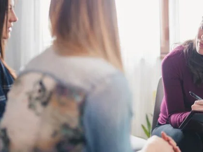 two woman talk to another woman who is making nores on a clipboard