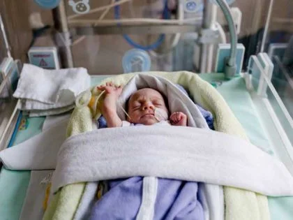 small baby lying on back in an incubator