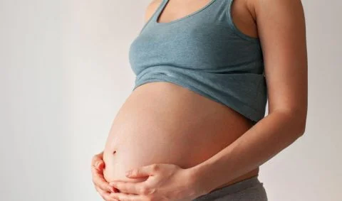 Multidisciplinary Approaches to Maternal Health - pregnant woman in grey vest holding her pregnancy bump