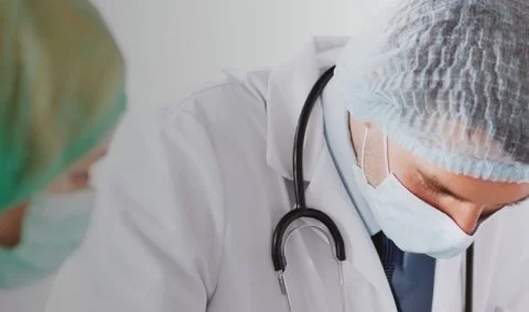 male doctor with stethoscope around neck wearing mask and head covering