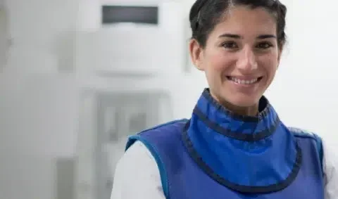 clinical oncology - female practitioner in blue protective top smiles