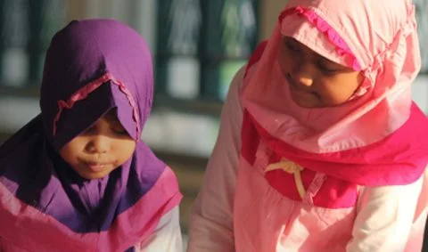 two young girls in colourful clothes one in purple and one pink