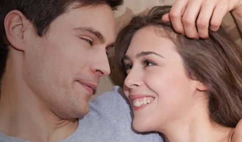 Sexual and Reproductive Health - man and women lie in bed smiling at each other