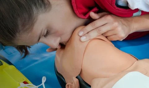 woman performing mouth-to-mouth on a medical dummy