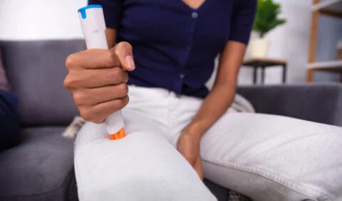 Anaphylaxis course - woman in white jeans and blue top presses EpiPen to thigh