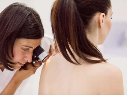 Dermatologist examining skin patient with dermatoscope