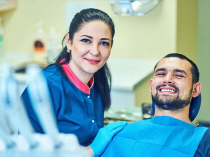 Female Egyptian dentist, smiling at camera with happy patient.